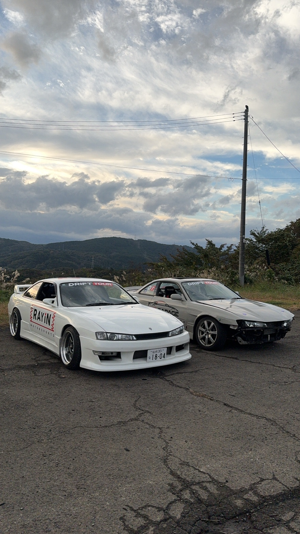 Two drift cars sliding in tandem at a Japanese circuit
